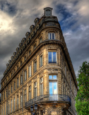 A grand, ornate building with a corner balcony.