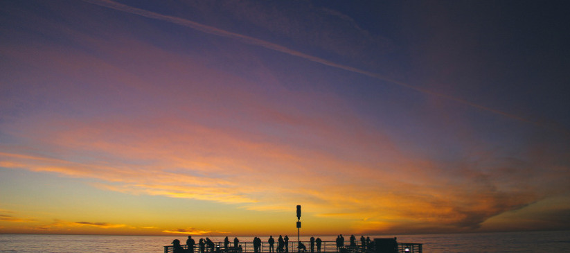 A group of people near the seaport at a sunset